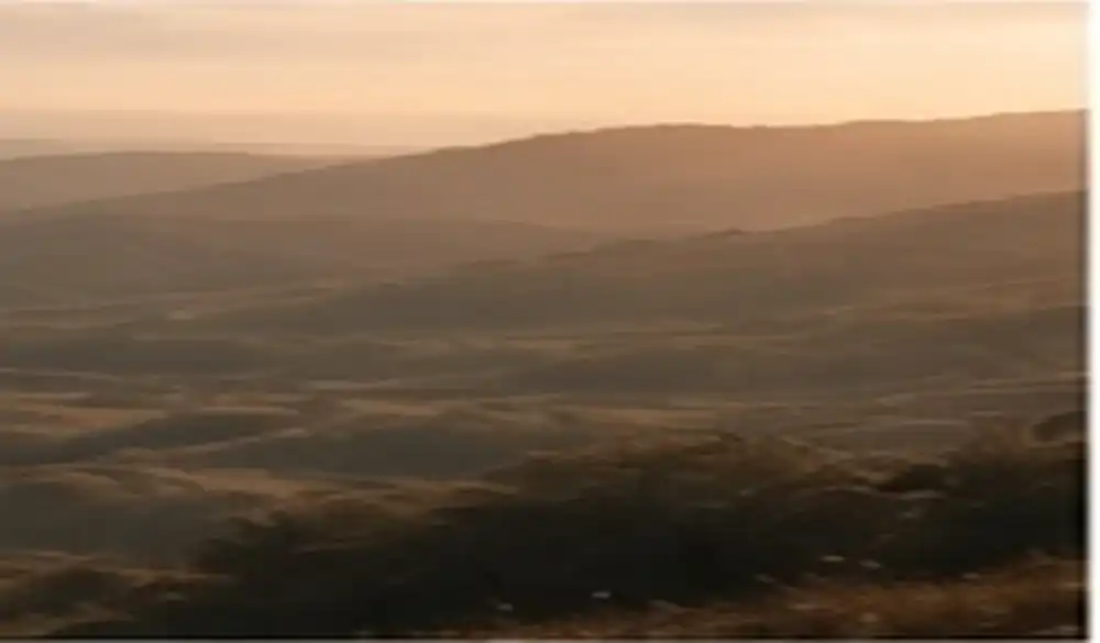 Paisagem de colinas em tons terrosos ao fim da tarde